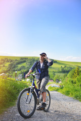 Fototapeta premium Young woman is traveling with a bicycle in the summer mountains