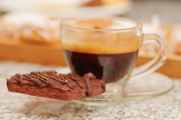 Close up of hot coffee with a chocolate cake in a blurred background