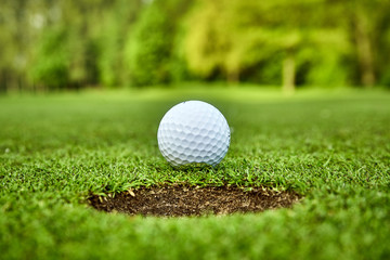 Golf ball on the green. golf ball on lip of cup