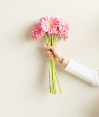 Bras de femme avec tatouage de poignet d& 39 amour tenant des gerberas roses - amour, concept de cadeau