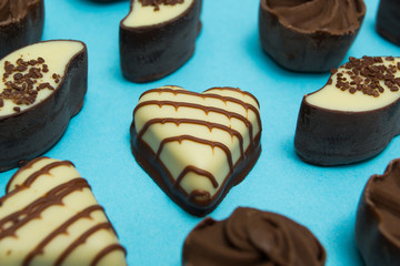 A set of chocolate candies in different shapes isolated on a blue background. Selective focus.