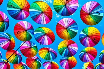 Fototapeta na wymiar Rainbow umbrella on sky background. Many colorful umbrellas. umbrella street decoration