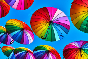 Fototapeta premium Tęcza parasol na nieba tle. Wiele kolorowych parasoli. parasolowa dekoracja uliczna