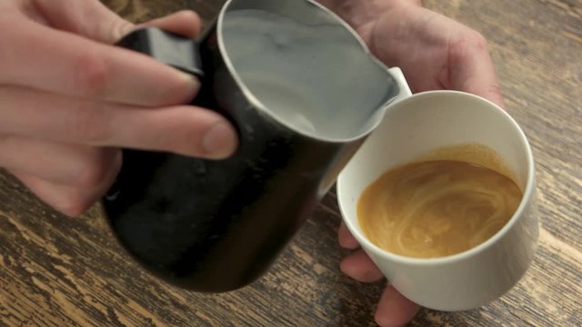 Pouring latte art. Mug with frothy coffee.