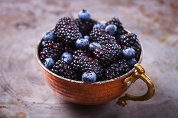 Berry Fresh in a copper cup on the Metal Background. Blackberries,Blueberry.Food or Healthy diet concept.Super Food.Vegetarian.Copy space for Text.selective focus.