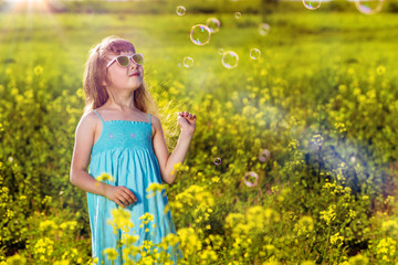 Girl in a blue dress in a field. Yellow flowers in summer. Sunny morning in nature.