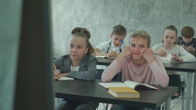 Unhappy schoolgirl in class listen to a teacher