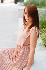 Woman in long dress sitting on city street