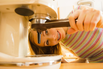 Woman in kitchen making coffee from machine