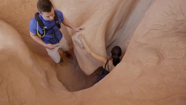 Medium slow motion high angle shot of couple hiking in slot canyon / Escalante, Utah, United States