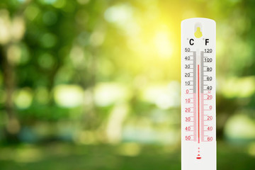 thermometer on a green nature background and temperature measuring, environment concept. - obrazy, fototapety, plakaty