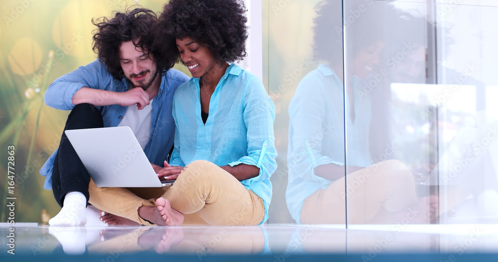 Wall mural multiethnic couple using a laptop on the floor