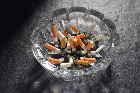 Many cigarette butts and ashes piled in an ashtray