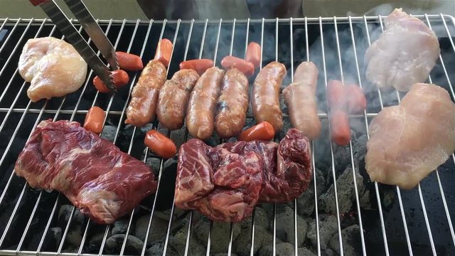 Beef, chicken, small and big sausages on grill for BBQ party with friends