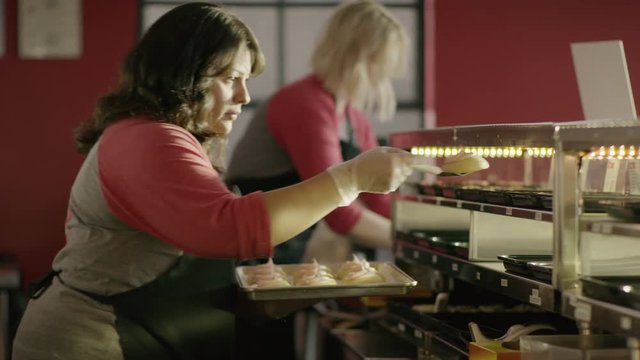 Medium slow motion shot of baker placing cookies in bakery display case / Salt Lake City, Utah, United States