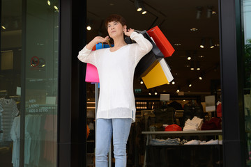 Happy woman at the mall holding shopping bags and smiling