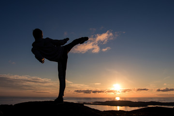 Silhouette of man doing TaeKwonDo or Karate kick in the sunset. Martial art concept.