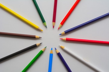 Different colored pencils pointing at each other portraying diversity and strength shot from a top angle on a white background