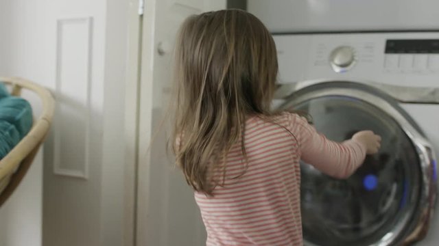 Medium shot of girl catching pot holder and placing in washer / Provo, Utah, United States