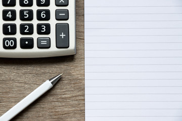 Blank note book with pen and calculator on wood background