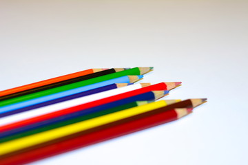 Different colored pencils stacked next to each other portraying diversity and strength shot from a side angle on a white background