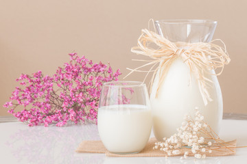 A glass of milk and a pitcher of milk on marble table.