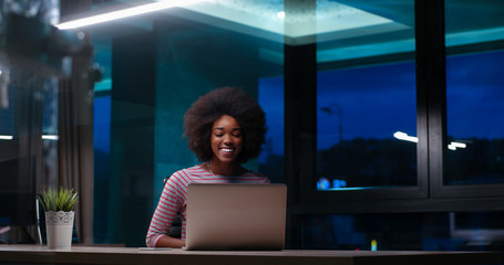 black businesswoman using a laptop in night startup office