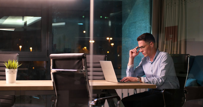 man working on laptop in dark office