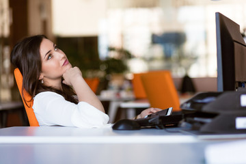 Happy pensive businesswoman planning and looking sideways at office