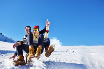 Fototapeta na wymiar Young Couple Sledding And Enjoying On Sunny Winter Day
