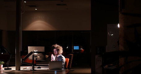 Plakat man working on computer in dark office