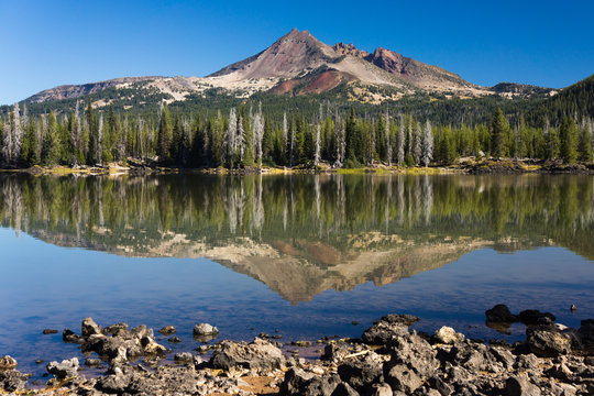 Volcanic mountain in morning light reflected in still waters of foreground lake