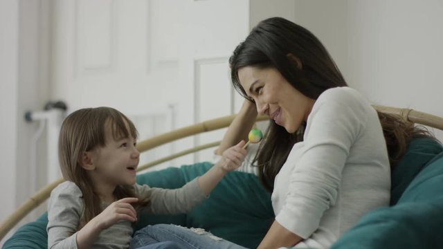 Medium shot of mother and daughter sharing lollipop / Provo, Utah, United States