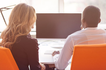 Two creative millenial small business owners working on social media strategy using a computer