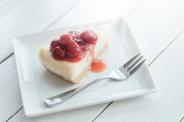Delicious with dessert a piece of cherry cheesecake on white tone wooden table