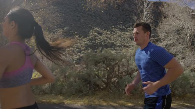 Medium panning shot of man flirting with woman while running / Antimony, Utah, United States