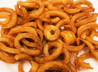 Crispy baked curly fries on a white background
