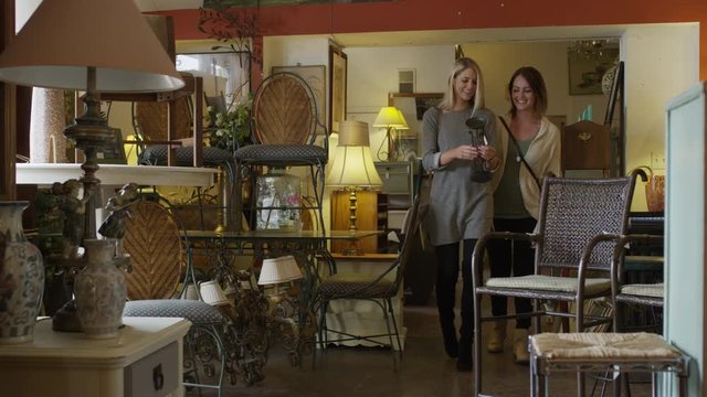Medium shot of women examining sculpture in antique store / Salt Lake City, Utah, United States