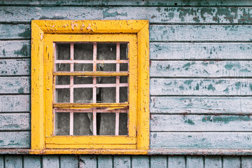 yellow window on green wooden wall of abandoned house