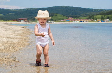 Child on the beach in rubber shoes. Children's bathing shoes. 