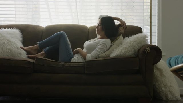 Medium slow motion shot of woman falling onto sofa and napping / Provo, Utah, United States