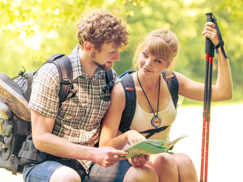 Hikers backpackers couple reading map on trip.