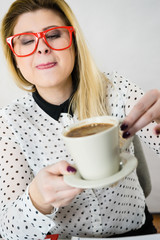 Happy woman at office drinking hot coffee