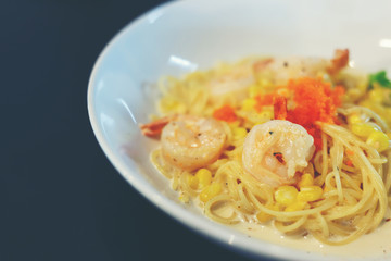 Carbonara spaghetti cream with shrimp in white dish put on black table.