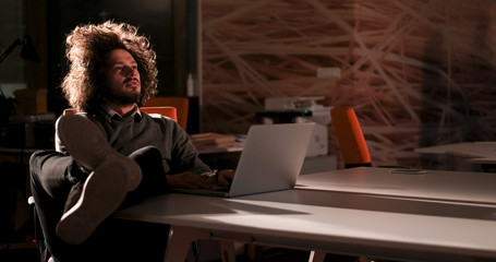 Obraz na płótnie Canvas businessman sitting with legs on desk at office