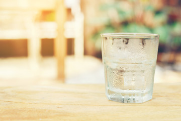 A glass of cold pure water put on the wooden table setting in the garden.