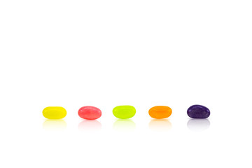 Color jelly beans are lined up in rows on white background. Conceptual sort by order.