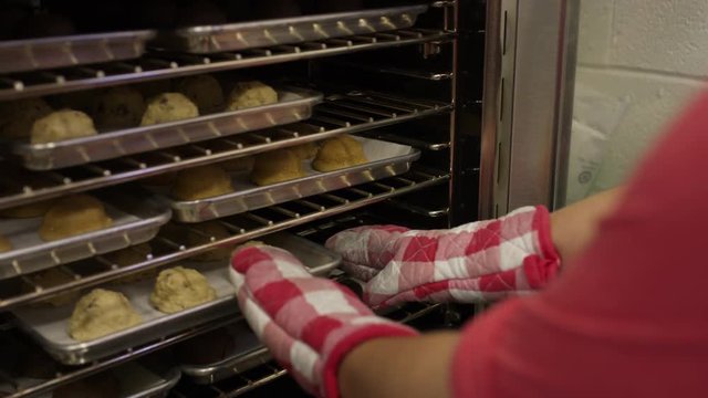Close up high angle shot of baker turning trays in oven / Salt Lake City, Utah, United States