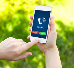female hands holding a white phone with ringing tube on the screen