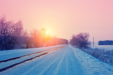 Rural winter landscape. Sunrise over snowy road